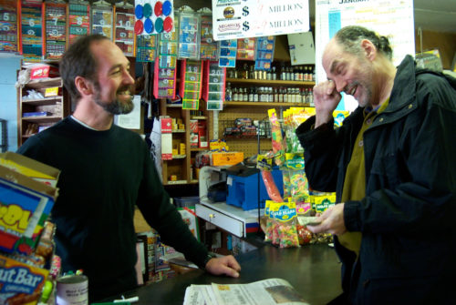 General store owner and a customer share a laugh.