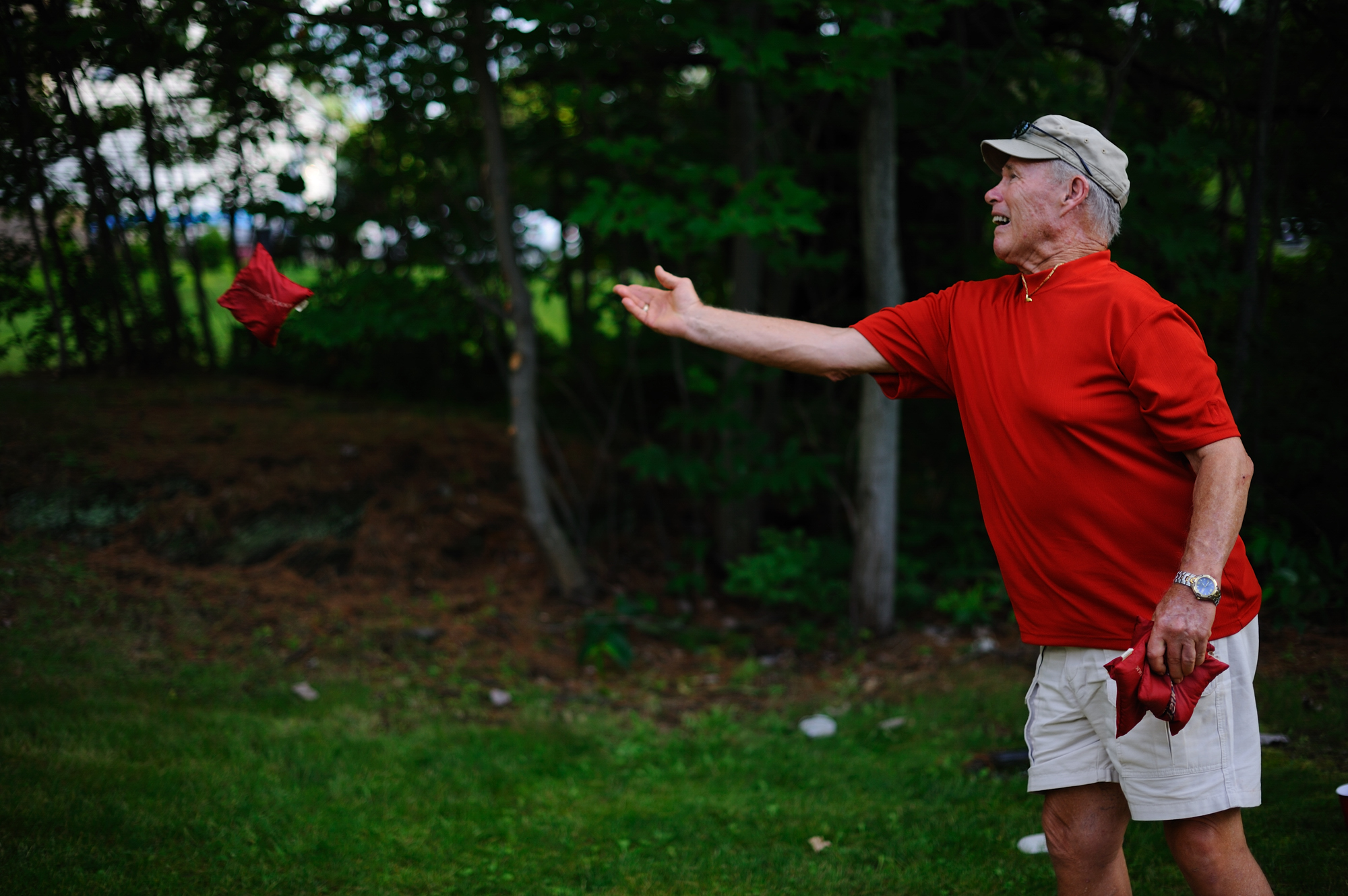 Red shirt, older gentleman, plays Cornhole.
