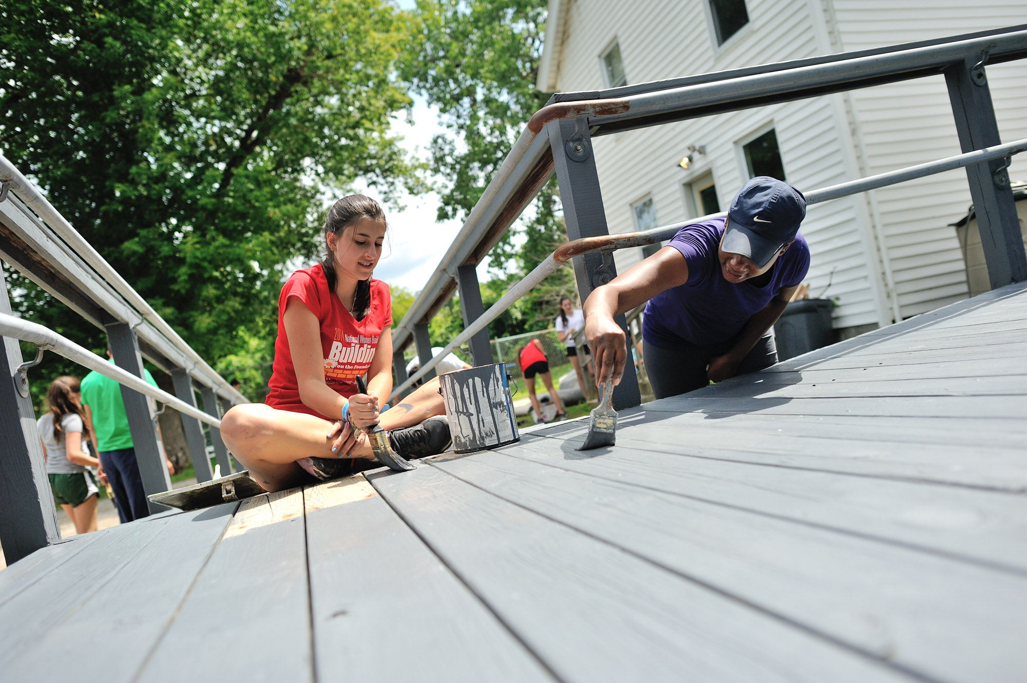 Young Habitat volunteers paint a handicap ramp.